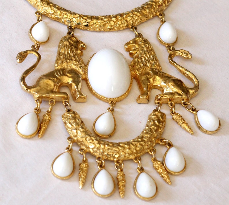 皇家狮子·巴洛克风格项链；罕见的、未签名的DonaldStannard项链；该系列以大块凸圆形宝石和金色皇家狮子为特色；镀金/白色树脂；70年代制造；完好、极佳复古状态（暗点为反光）；单股链从头到尾长 22 英寸，中间主体结构为一个 6 ¼ 英寸长、5 英寸宽（20150226）/图丢失