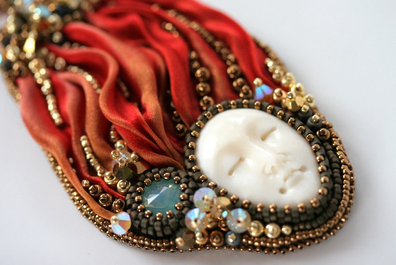 ③.「异域女神·脸骨」Shibori珠饰项链Merida；斯洛伐克手艺人ZuziHake；项坠—手工雕刻脸骨凸圆形宝石/Shibori的 Firefall扎染丝带/施华洛世奇（太平洋蛋白石/白蛋白石2XAB/金和青铜双锥）/青铜和金色日本Toho米珠/巧克力色Ultra Suede鹿皮绒制成；项绳—青铜Toho圆柱珠和Fireline，饰有装饰性铜质搭扣；项绳长40厘米，吊坠8.5×5厘米；孤独品（20141128）/图丢失