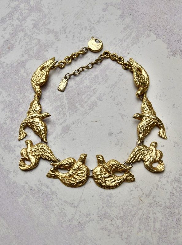 ②.鸽子飞鸽群YSL收藏级短项链；圣罗兰（Yves Saint Laurent）；由 Goossens 设计，灵感源自艺术家 Braque，延续自1988年冬季高级定制系列中那件饰有飞鸽刺绣的晚礼服。项链以飞翔的金色鸽群为造型，极具标志性。弹簧扣处刻有签名，链尾配有带签名的吊牌，些许岁月与使用痕迹；项链主体部分成色佳。经典而极具辨识度的设计之一。镀金；法国制造80年代YSL10422