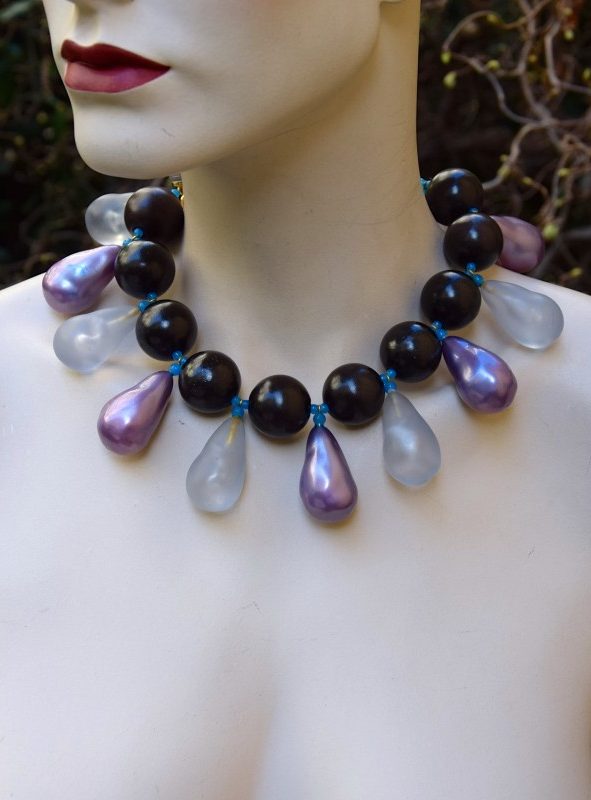 ②.木珠紫色磨砂相间水滴垂饰罕见YSL短项链；圣罗兰（Yves Saint Laurent）；难得一见的Rive Gauche短项链项圈，深色木珠与紫色珠饰交织，辅以磨砂树脂垂饰与细小蓝色玻璃珠连接，质感丰富。金色金属钩扣闭合，链尾可调，附签名铭牌。整体为良好中古状态，伴轻微岁月痕迹；法国制造70年代YSL4696