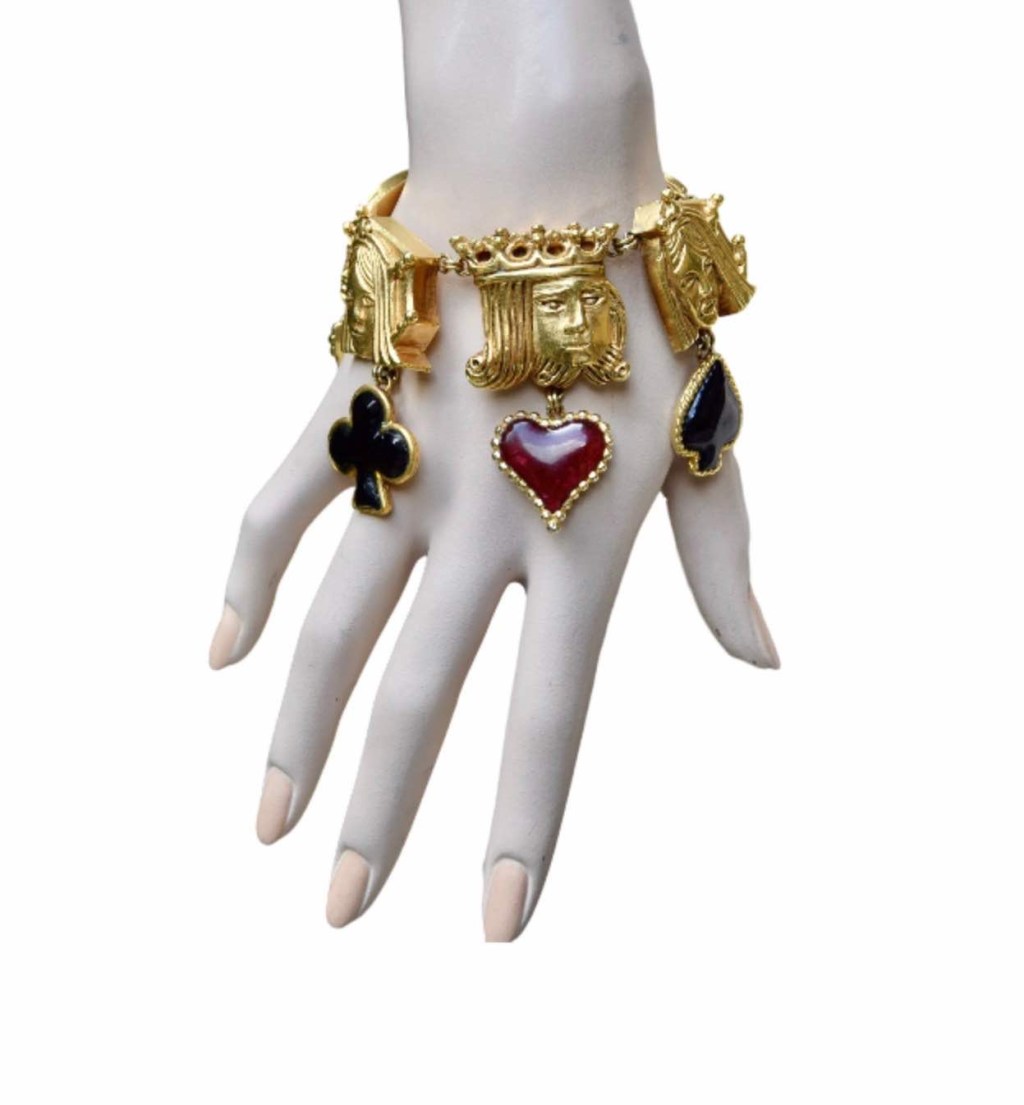 ②.国王王后侍从·头像扑克牌主题IC手链；华美且极为罕见的Isabel Canovas作品，出自“Les Jeux”系列（1991年冬季）。以扑克牌中的国王、王后与侍从头像为主题，每一枚皆配有对应的浇铸玻璃符号吊饰：红与黑两色，分别对应红心、方块与梅花、黑桃，隐含情感、财富、行动与命运的象征，构思巧妙而富有趣味。链条搭配龙虾扣闭合。背面刻有签名。镀金；法国制造IC7681