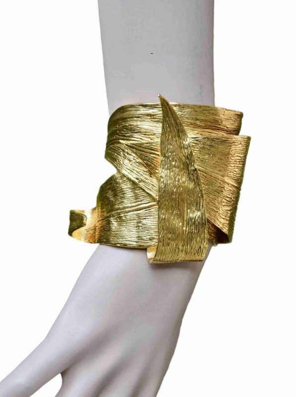 ②.香蕉叶纹理环绕·东方风情·YSL手镯；圣罗兰（Yves Saint Laurent）华美重工的开口手镯，以层叠环绕的蕉叶造型呈现，仿佛沿腕缠绕，立体感强烈。背面刻有签名。附原始盒与防尘袋。镀金；法国制造YSL10640