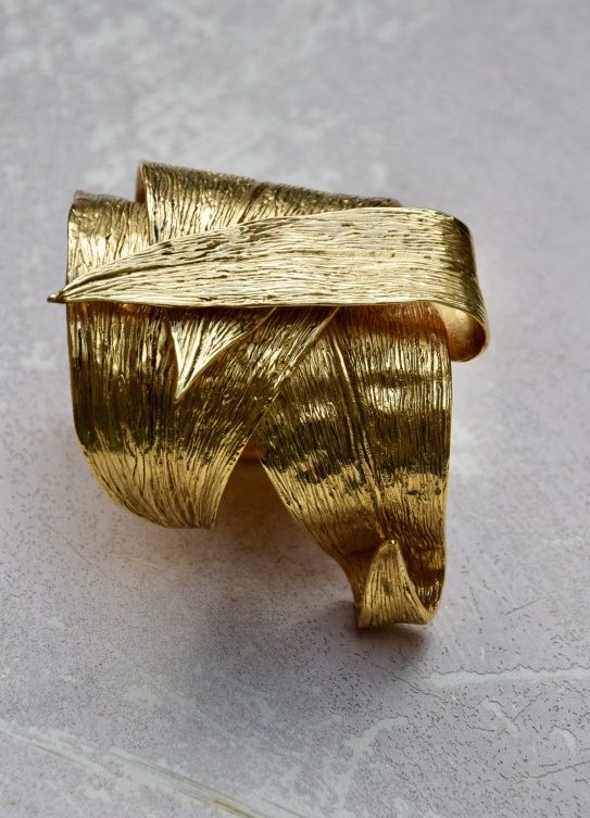 ②.香蕉叶纹理环绕·东方风情·YSL手镯；圣罗兰（Yves Saint Laurent）华美重工的开口手镯，以层叠环绕的蕉叶造型呈现，仿佛沿腕缠绕，立体感强烈。背面刻有签名。附原始盒与防尘袋。镀金；法国制造YSL10640