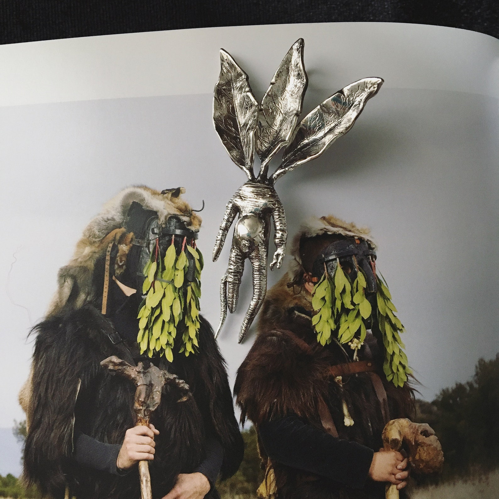 ②.曼德拉草人形·”毒植”系列·项坠；土耳其手艺人Göksu作品；曼德拉草自古被视为具有魔力的人形植物，与女巫、炼金术与古老草药学密切相关。它既是传说中的魔药成分，也常被佩戴为护身符，象征力量、命运与隐秘的掌控。作品兼具奇幻、超自然、俏皮与写实感，由叶片、花朵（可选）和根部构成。材质为纯银，附纯银链；花朵可选版本有无花、纯银花、玫瑰金镀铜花；约6.5×3.5cm。古老失蜡法，纯手工雕刻制作｜x3626