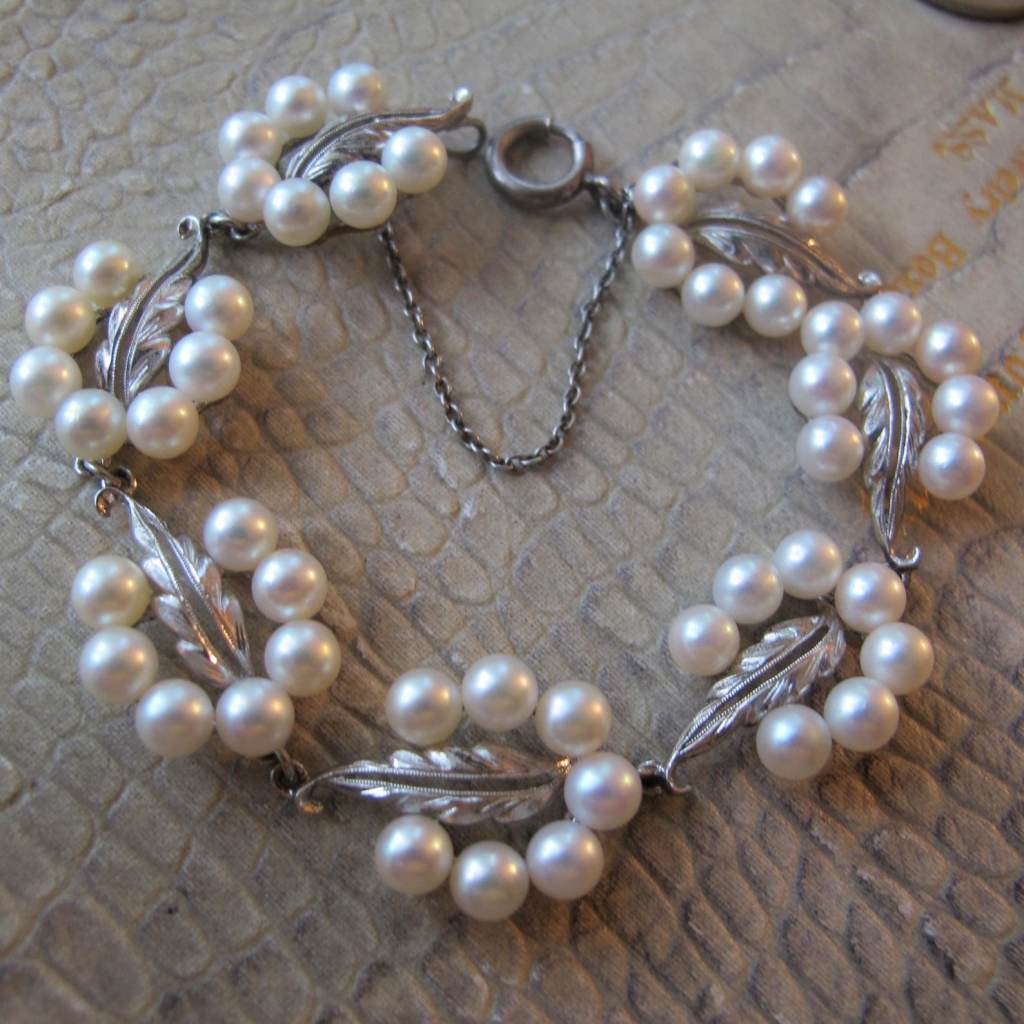 ②.御木本·Mikimoto珍珠花叶链式美人手链，日本制，约1950–60年代。由花叶形面板连接而成，点缀白色珍珠，带有淡淡粉调光泽。整体结构细致而柔和，呈现出典型的中世纪优雅气质。背面带有Mikimoto标记（M）及银质印记（S），配有安全链与老式弹簧扣。材质：银/珍珠（约5mm）；长约 7in(17.78cm) x宽约&nbsp;1.6cm；藏于美国