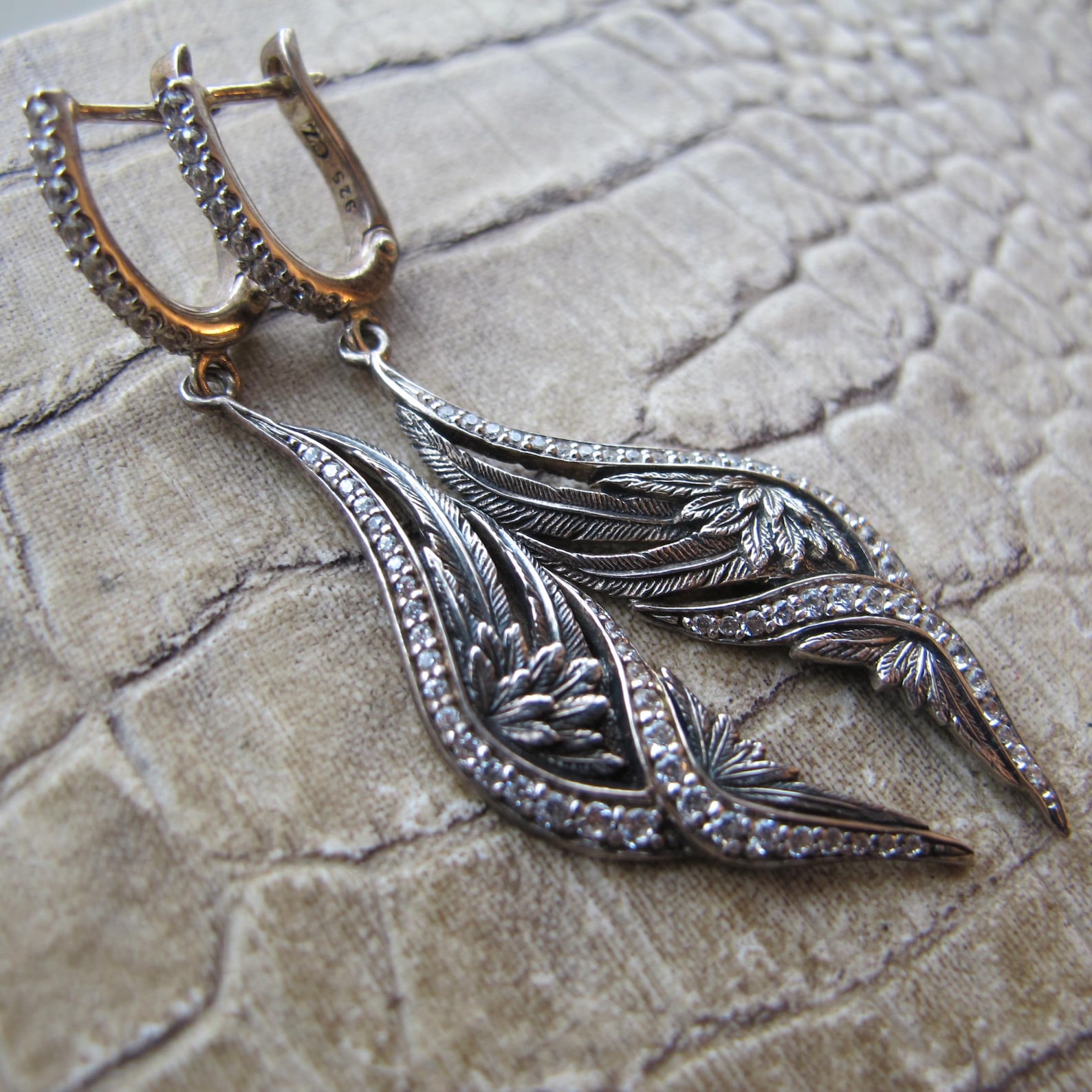 ②.天使之翼·装饰艺术风格垂坠SK耳环，90年代泰国制作；925纯银打造，镶嵌锆石。线条呈展开的羽翼形态，轻盈下垂，在细微的摆动中呈现柔和光泽。整体结构简洁而优雅，带有一丝古典气息。背面带有设计师签名及925银标记。925纯银/锆石（CZ: cubic zirconia）；约5.5cm×1.1cm｜x5226