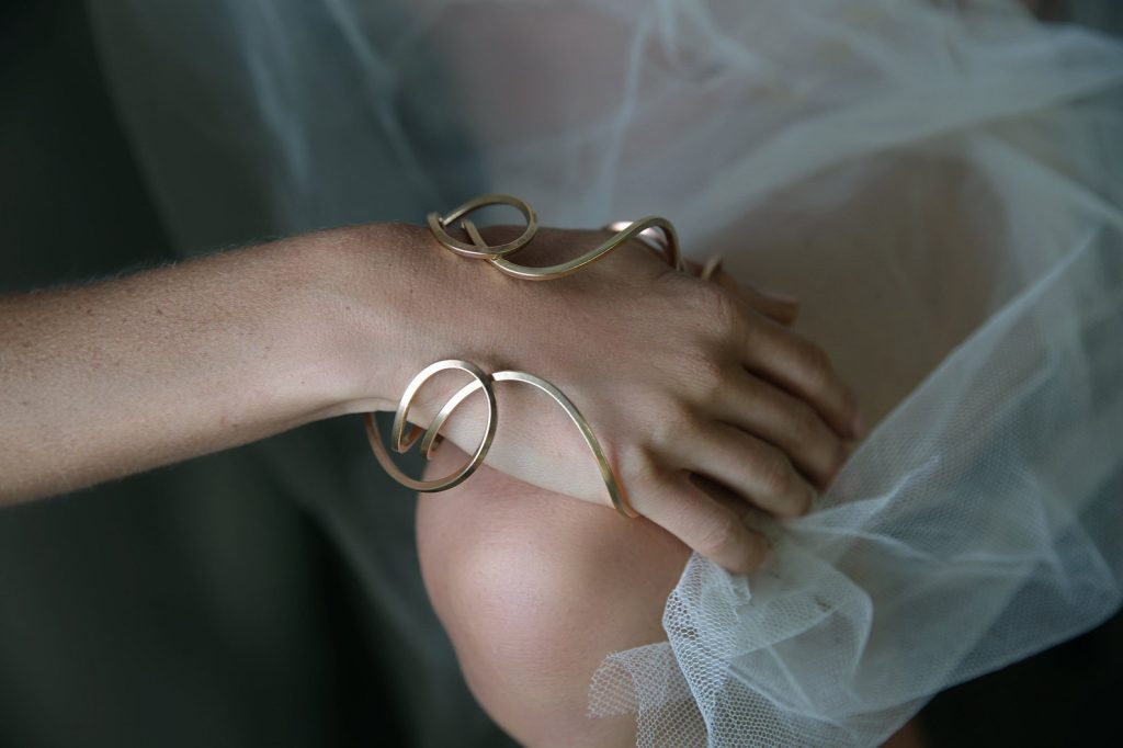 ②.大地女神瑞亚Rhea手镯·Celestial（古希腊天神）系列；英国手艺人Emma作品；以曲线为核心的开放式结构，跨越手背与手腕之间。可正反佩戴，在手腕周围形成近似“光环”的轮廓，形成一个轻微的「场域」，象征自然母神的围合与保护（承托）。均码（手环略具弹性，可微调贴合手掌），亦可定制尺码；材质有（黄铜/镀金/玫瑰金镀层/925纯银）四种可选