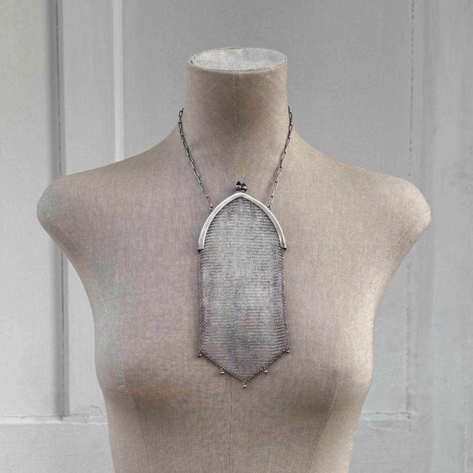 ②.ArtDeco网状晚宴1920s锁子甲手袋；细密编织的金属网身自然垂落，下缘呈尖形轮廓，并点缀小珠流苏。弧形金属框配以深蓝色圆拱琉璃宝石扣饰，在冷调金属中形成克制的色彩对比。网状结构随动作产生柔和流动与光泽变化，保留了20世纪初晚宴配饰特有的轻盈与精致。附原链条。手袋约18×9cm，链长约33cm，德国银/琉璃，1920年代制作；完好无损；西班牙｜x6726