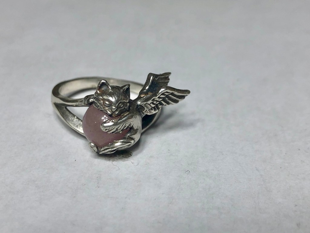 ②.天使猫咪怀抱宝石·童话气息·戒指环；美国手艺人Natia作品；「微小而重大的陪伴」；小猫镶嵌圆形宝石，由双爪与下巴托起，背部展开双翼，造型轻盈而完整。结构贴合手指，保留细节的同时兼顾佩戴舒适度。925纯银/天然宝石（图为玫瑰石英/粉晶，亦有多种宝石可选）；定制尺码。古老失蜡法纯手工制作