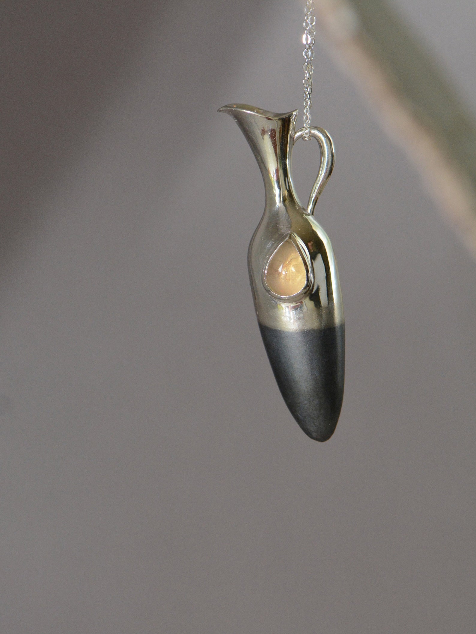 ②.「仍然感受和珍视」泪瓶项链；以色列手艺人Irina作品；新艺术+现代主义；这枚泪瓶将无形的悲伤凝固成形。不论是美人鱼之泪、天使之泪，还是人之泪，都在那宝石里闪烁微光。哀愁是生命经验的一部分；承认生活的荒谬，是走向力量与自我的前提。细长瓶身呈垂直延展形态，表面结合哑光与抛光质感；半部哑光处理氧化黑色银质的瓶身象征沉静，宝石如”泪滴般”清晰。925纯银/淡黄色拉长石或欧泊（可选）；项坠约5×1.2cm；有刻字服务｜x8626