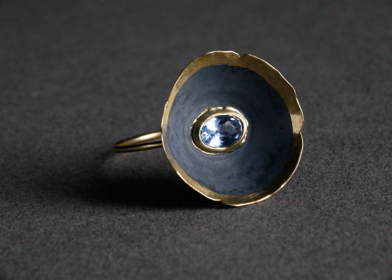 ②.「向内盛开的花儿」碗状罂粟花形戒指环；以色列手艺人Irina作品；新艺术+现代主义；细金戒托承托一枚戴着金色皇冠的黑银质“花碗”，边缘起伏，中央镶嵌海蓝宝。14k黄金/氧化黑925银/海蓝宝；花部约20mm，指环臂约1.3mm；定制尺码；有刻字服务｜x9126