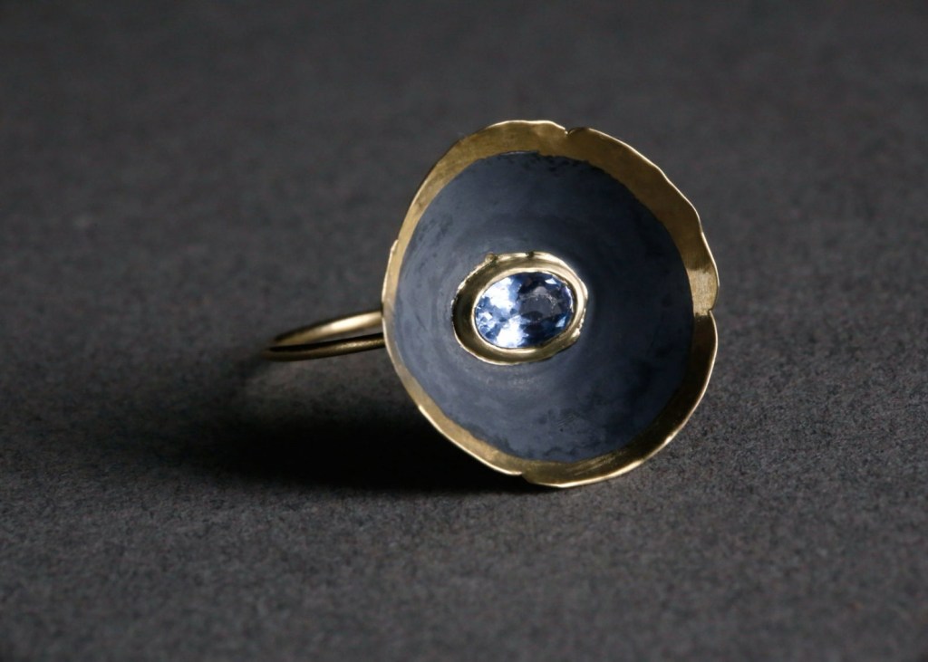 ②.「向内盛开的花儿」碗状罂粟花形戒指环；以色列手艺人Irina作品；新艺术+现代主义；细金戒托承托一枚戴着金色皇冠的黑银质“花碗”，边缘起伏，中央镶嵌海蓝宝。14k黄金/氧化黑925银/海蓝宝；花部约20mm，指环臂约1.3mm；定制尺码；有刻字服务