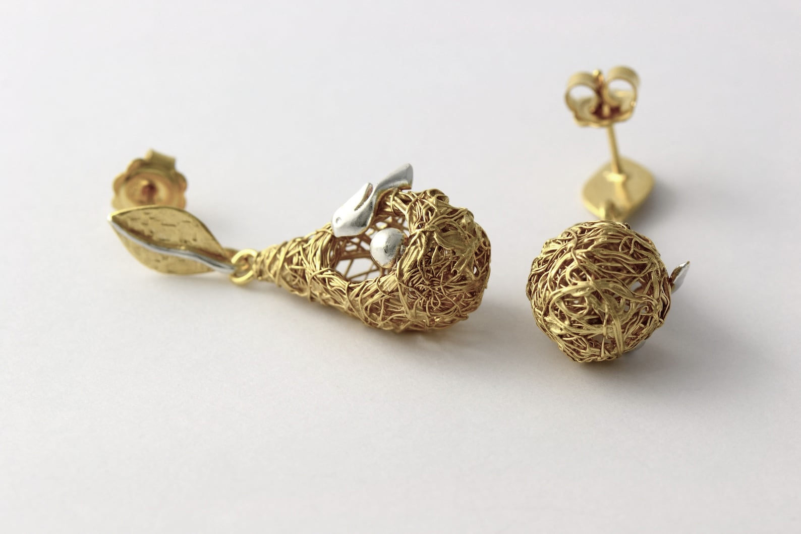②.「爱与安心之所」鸟与巢耳钉耳环;英国手艺人Magnolia作品;自然主义/现代主义;一个金丝鸟巢(灵感源自亚马逊的织巢鸟(Oropendola)):一只银鸟温柔守望着一只银蛋。巢穴穿过树枝圆环,彼此嵌合,像一个不断循环的场景。它像极了一种关于“家”的意象,或是关于守护、孕育与存留的记忆。鸟与巢的关系是庇护,也是责任;是安放,也是牵引。正如”家”不只是温柔的归处,也关乎时间、付出,以及持续发生的循环。镀24k金纯银+纯银(鸟与蛋);整体约4cm×1.1cm(手工编织,每件略有差异)|x9526