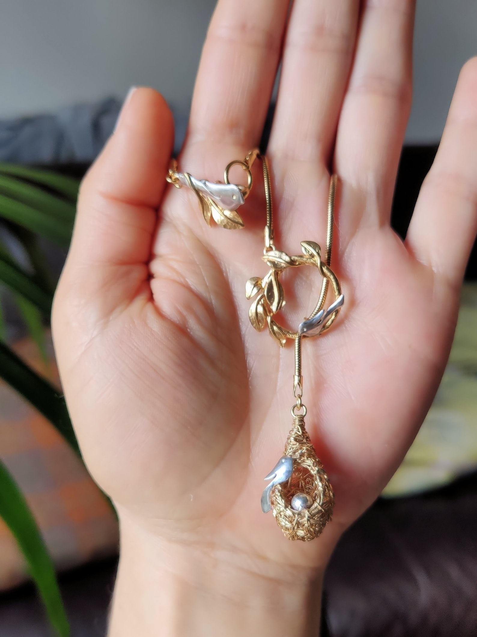 ②.「爱与安心之所」鸟与巢项链；英国手艺人Magnolia作品；自然主义/现代主义；一个金丝鸟巢（灵感源自亚马逊的织巢鸟(Oropendola））：一只银鸟温柔守望着一只银蛋。巢穴穿过树枝圆环，彼此嵌合，像一个不断循环的场景。它像极了一种关于“家”的意象，或是关于守护、孕育与存留的记忆。鸟与巢的关系是庇护，也是责任；是安放，也是牵引。正如”家”不只是温柔的归处，也关乎时间、付出，以及持续发生的循环。镀24k金纯银+纯银（鸟与蛋）；巢约3cm×1.3cm（手工编织，每件略有差异），链长约50cm｜x9426