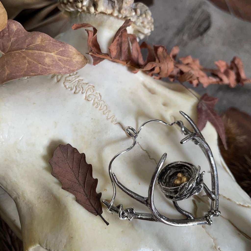 ②.「万物并生」“巢之冠”鹿角项坠项链；土耳其手艺人Göksu作品；由鸟巢、鹿角、常春藤花环和三颗金蛋组成。设想鸟儿在一只雄壮美鹿的鹿角上筑巢，那鹿角如树枝般延展；呈现出自然的美、和谐与神秘，并带有森林般的诗意。不同生命形态在同一结构中”共生”，形成一种自然而然的秩序与平衡，也让人想到道家对于自然的理解：万物各得其所，彼此依存，不相主宰，却自成和谐。925纯银+镀金黄铜（金蛋），主体约为5cm直径，附纯银链（40/50/60厘米可选）。古老失蜡法，纯手工雕刻制作｜x9826