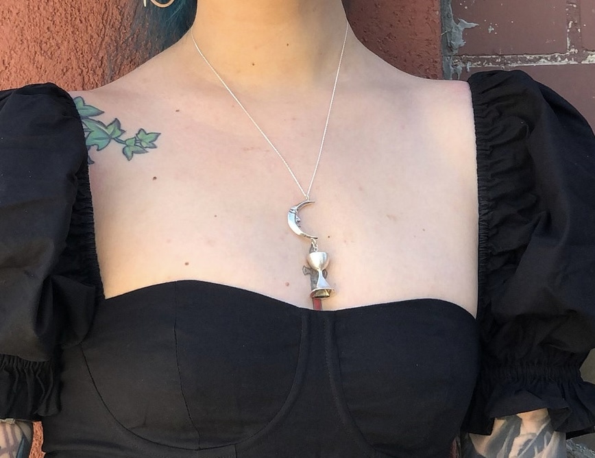 ②.「饮月：致节律、柔性与内在」新月高脚杯项坠项链；土耳其手艺人Göksu作品；由两个相互垂坠的元素组成：一弯带有人脸的新月与一只高脚杯。呈现出超现实、梦境般且略带奇趣的风格。在神话中，月亮常与女性神祇相连，象征自然力量与相对独立的领域；在现代心理学中，它则常被用于指向情绪、潜意识与内在的世界。925纯银，吊坠总长约7.2cm（月亮约2.5cm/杯子约2.8cm）附纯银链（40/50/60厘米可选）。古老失蜡法，纯手工雕刻制作｜x9926